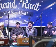 A group of men are sitting on a stage playing instruments.
