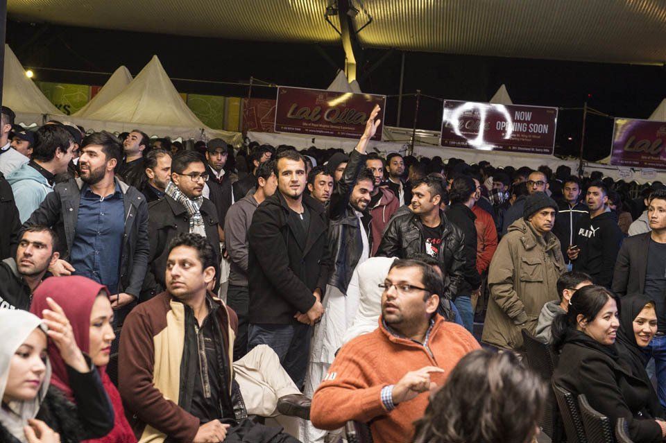 A large group of people are sitting in a tent at a concert.