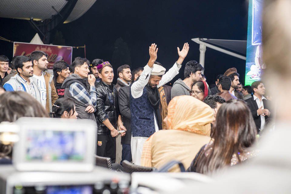 A group of people are standing in a room with their hands in the air.