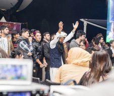 A group of people are standing in a room with their hands in the air.