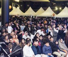 A large group of people are sitting in front of a stage at a concert.