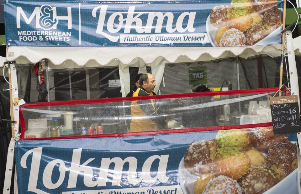 A man is standing in front of a tokma food stand