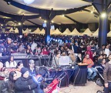 A large crowd of people are sitting in a large room watching a concert.