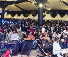 A large group of people are sitting in a large room under a tent.