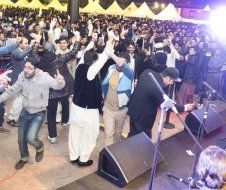 A large group of people are dancing in front of a stage.