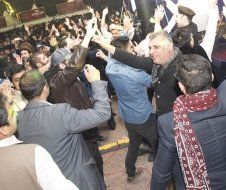 A crowd of people are standing in a room with their hands in the air.