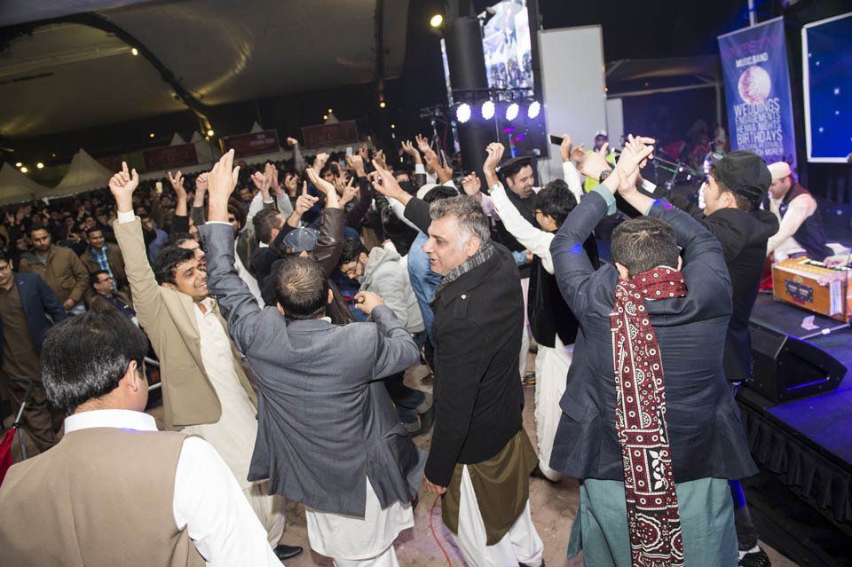 A group of people are dancing in a room with their arms in the air.