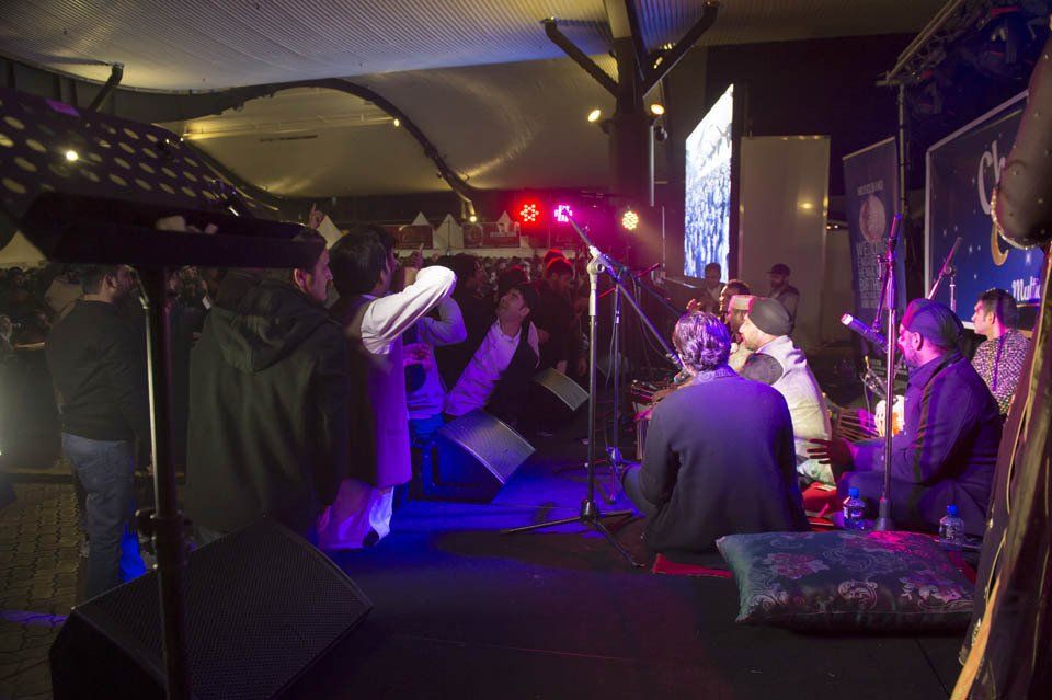 A group of people are sitting on the floor at a concert.