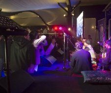 A group of people are sitting on the floor in front of a stage at a concert.