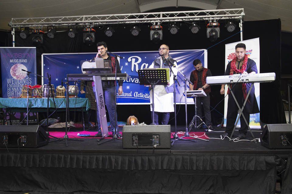 A group of men are playing keyboards on a stage in front of a sign that says ' rock ' on it