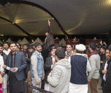 A group of people are standing in a room under a tent.