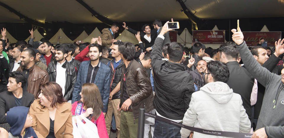 A crowd of people are standing in a line at a festival.