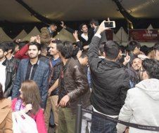 A group of people are standing in a crowd taking pictures with their phones.