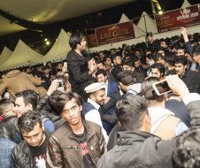 A crowd of people are gathered in a tent at a party.