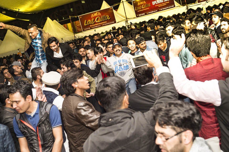 A crowd of people are gathered in a room with a sign that says coca cola