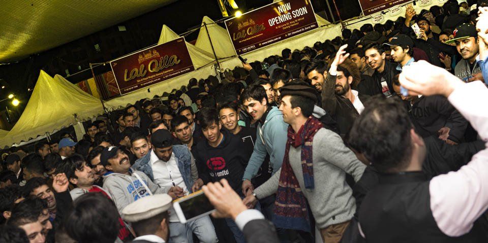 A man is taking a picture of a crowd of people at a festival.
