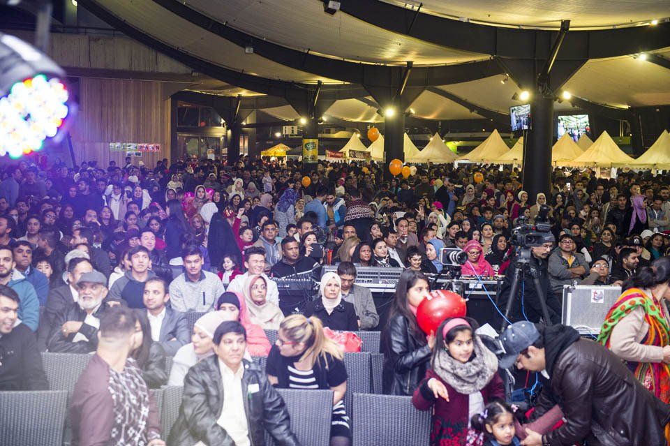 A large crowd of people are sitting in a large room at a concert.