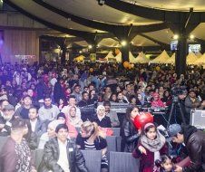 A large crowd of people are sitting in a large room at a concert.