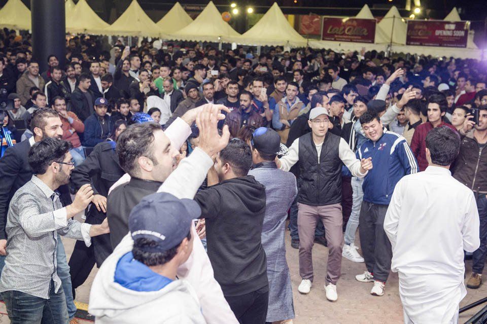 A large group of people are dancing in a tent.