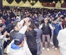 A large group of people are dancing and taking pictures at a party.