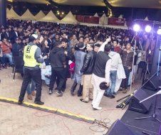 A crowd of people are standing in front of a stage at a concert.