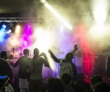 A group of people are dancing on a stage at a concert.
