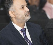 A man in a suit and tie is sitting in a crowd of people.