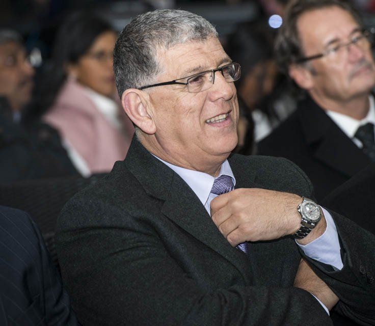 A man in a suit and tie is smiling and wearing a watch