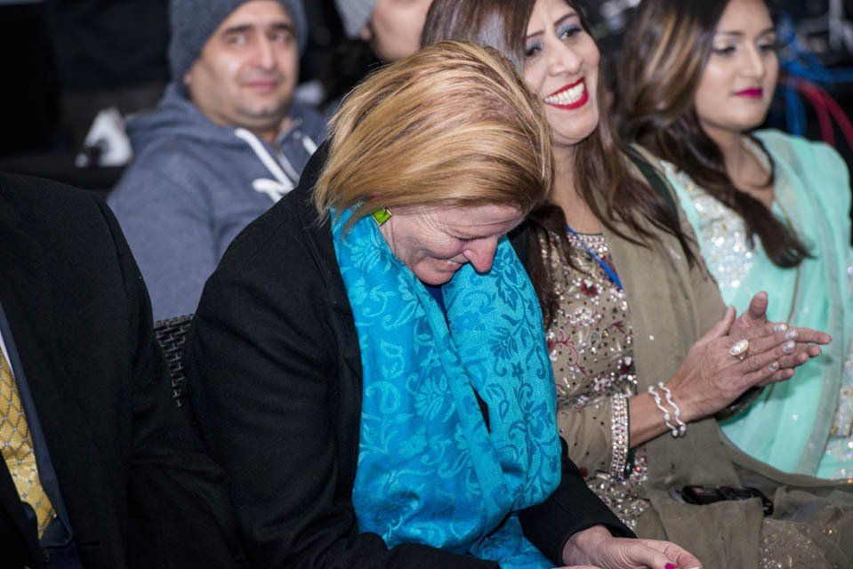 A woman in a blue scarf is sitting in a crowd of people.