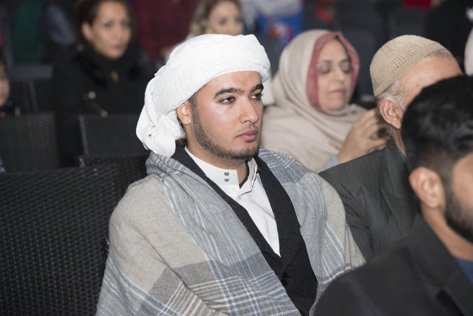 A man wearing a turban is sitting in a crowd of people.