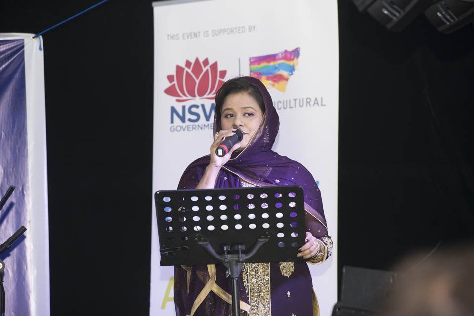 A woman is singing into a microphone while standing at a podium.
