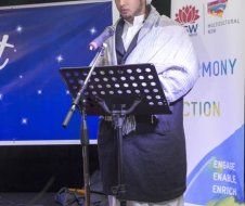 A man is standing at a podium speaking into a microphone.