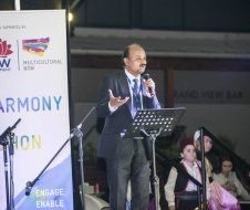 A man in a suit and tie is standing at a podium speaking into a microphone.