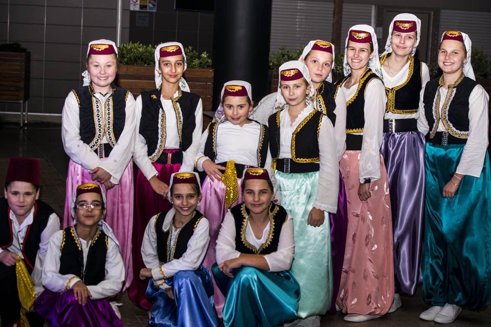 A group of young girls in traditional costume are posing for a picture.