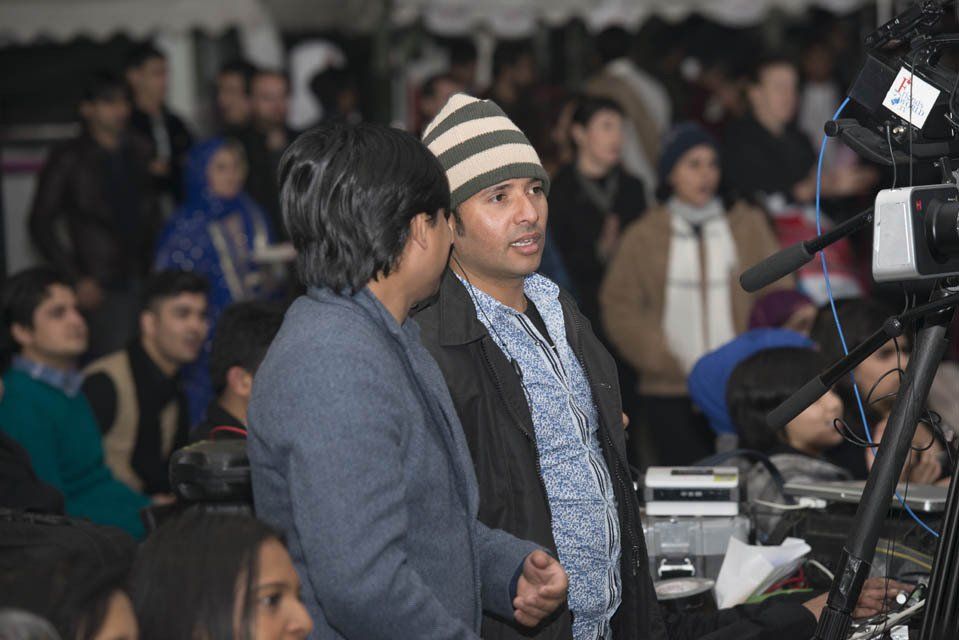 Two men are standing in front of a camera in a crowd.