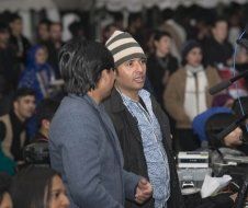 Two men are standing next to each other in front of a crowd.