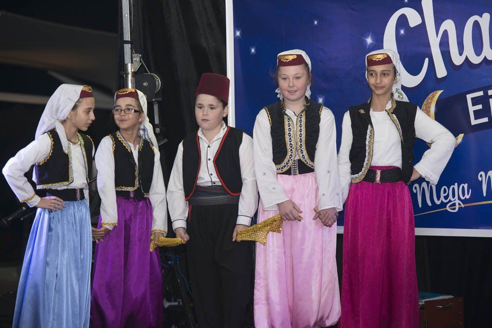 A group of children are standing in front of a sign that says mega