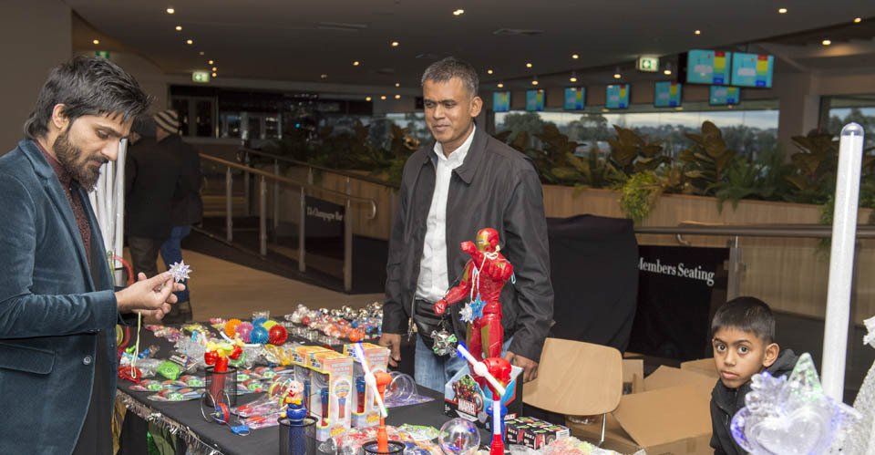 A group of men are standing around a table with toys on it.