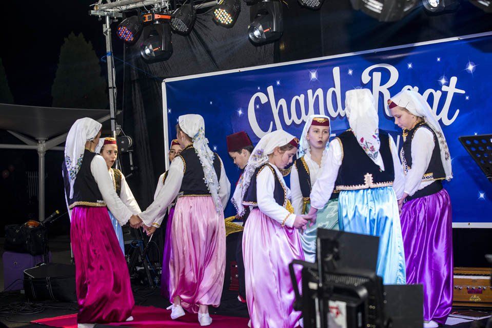 A group of people are dancing in front of a sign that says chandi raat