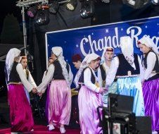 A group of people are dancing on a stage in front of a sign.