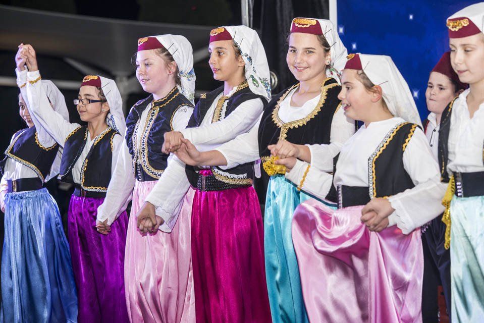 A group of young girls in traditional costumes are dancing on a stage.