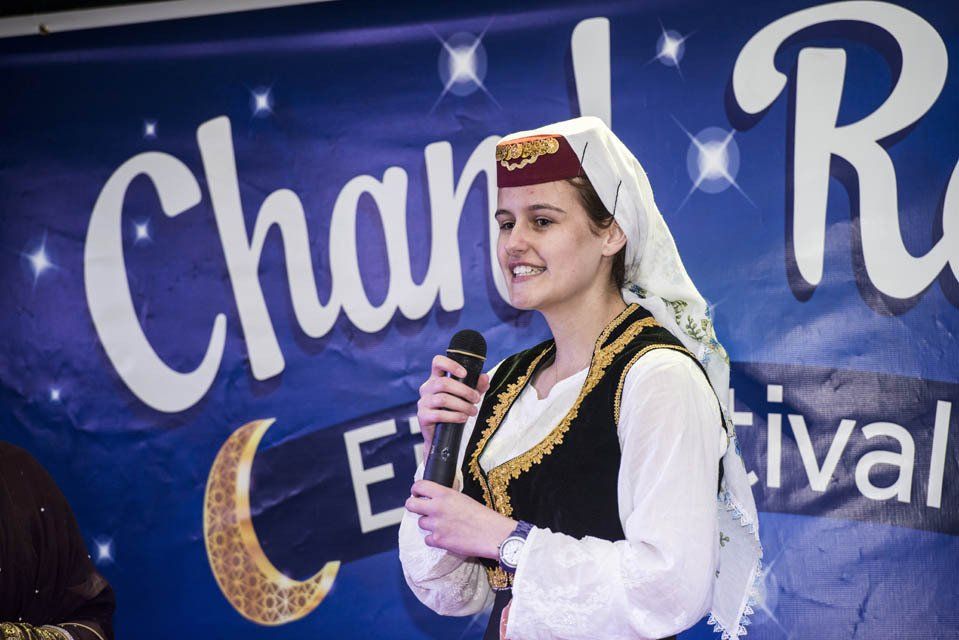 A woman is singing into a microphone in front of a banner that says char festival