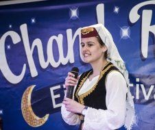 A woman is holding a microphone in front of a banner that says chante festive