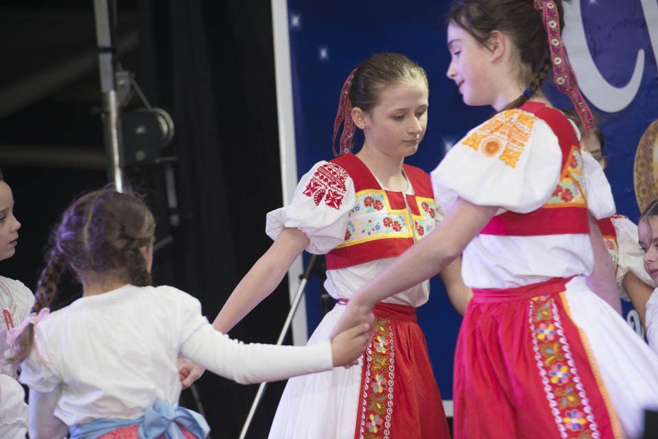 A group of young girls in traditional costumes are dancing on a stage.