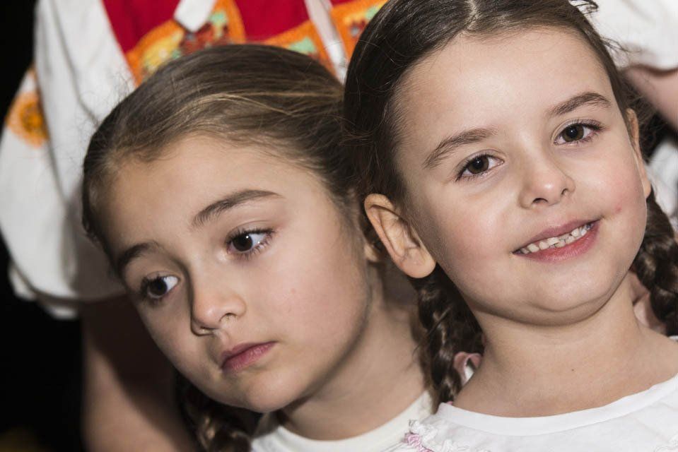 Two little girls are standing next to each other and smiling.