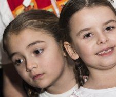 Two little girls are standing next to each other and smiling.
