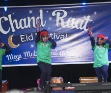 A group of people are dancing on a stage in front of a banner that says chand raat.