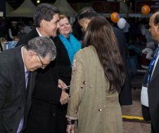 A group of people are standing around a woman in a green dress.