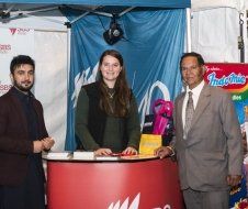 A group of people are standing around a red table.