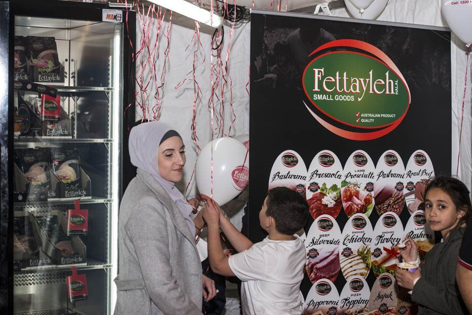 A woman is holding a balloon in front of a sign that says fettaylek.